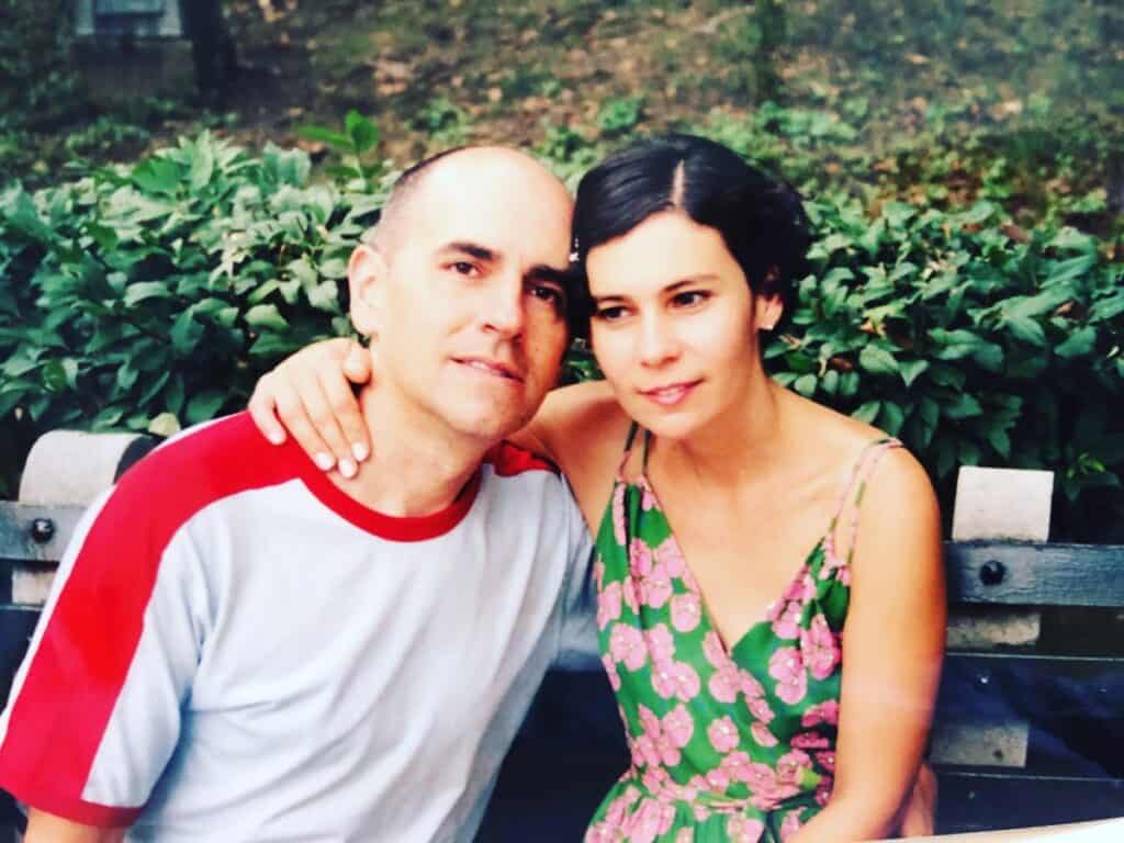 kim and matt sit on a bench in a forest