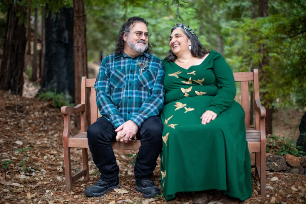 kathryn and joey sit after their forest wedding on a bench