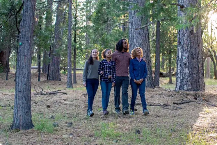 a family of four walk through the forest locking arms at a forest memorial