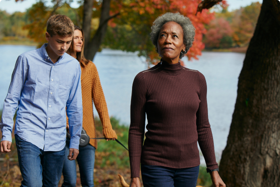 Three people walk together along a path near a lake.